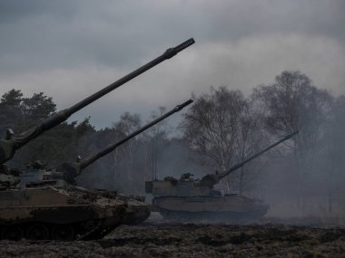 Çok sayıda PZH2000NL topçu aracı dramatik gökyüzü ile dumanlı savaş alanı koşullarında