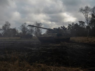 Bulutlu gökyüzünün altında mürettebatın bulunduğu askeri tank.