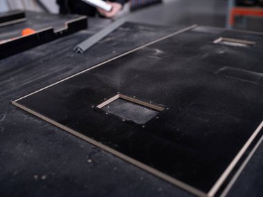 Teknik kesiklere sahip hassas siyah panel, CNC mekanik becerilerini ve hassasiyetini gösteriyor