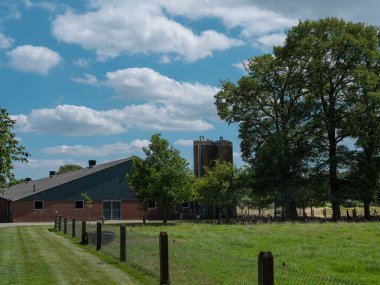 Tuğla bina siloları ve kırsal arazide çitle çevrili tarım tesisi.