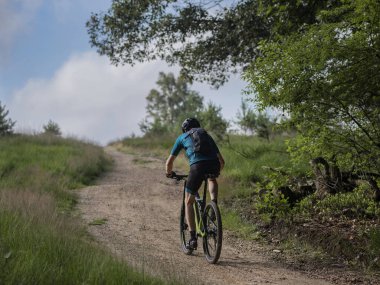 Dağ motorcuları kırsal alanda ağaçlar ve doğal manzarayla toprak yollarda geziniyorlar.