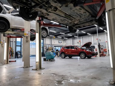 Araç şasi denetimi ve bakım alanını gösteren profesyonel oto tamir tesisini geniş açıdan görebiliyoruz.