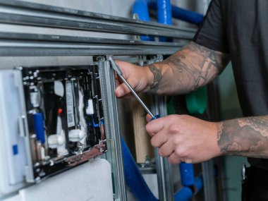 Hassas teknik ekipman montajı ya da onarımı üzerinde çalışan dövmeli ellerin yakın çekimi