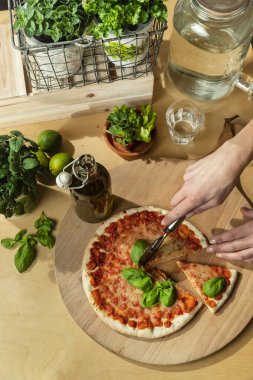 Tel kesilmiş pizza sepeti, taze bitkiler ve aşçılık seti.