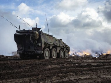 Eğitim sırasında arka planda sis perdesi efektleri olan askeri tekerlekli zırhlı araç yerleştirildi