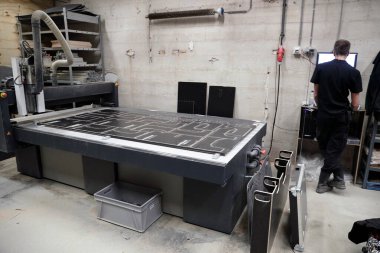 CNC makinesi arka planda çalışan bir işçiyle birlikte uçuş vakası üretim süreçlerini yönetiyor