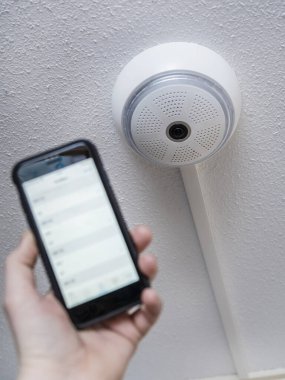 Tavana monte edilmiş ev güvenlik kamerası sistemini kontrol etmek için akıllı telefon.