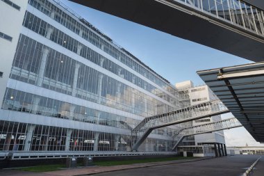 Kavisli cam tepe örtüsü ve çağdaş mimari tasarım öğelerine sahip modern ofis binası.