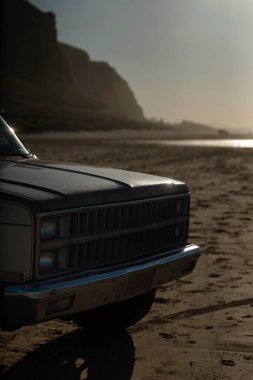 Arka planda dramatik uçurumlar olan İrlanda sahilindeki klasik SUV ön ızgarasının yakın çekimi