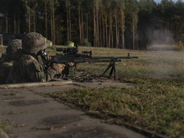 Ormanlık alanda makineli tüfekle savunma pozisyonu almış askeri silahlar.