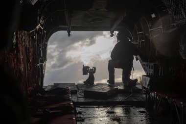 Siluetli asker uçuş operasyonları sırasında helikopter kapısına yerleştirildi.