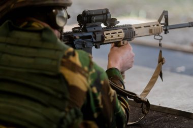 Gelişmiş optik ve aksesuarlı modern taktik tüfeği olan askerin yakın çekim görüntüsü