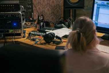 Prodüktör, profesyonel kayıt ekipmanı ve yazılımla birlikte ses çalışma istasyonunda çalışıyor.