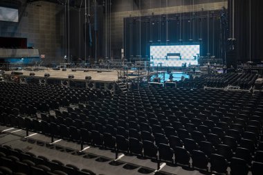 Binlerce koltuklu büyük konser salonu ışıklandırılmış sahne ve LED ekranlar