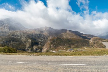 Dönek yolları ve bulutlu gökyüzünün altında dağlık binaları olan dramatik dağ manzarası
