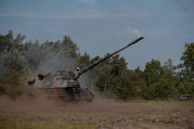 Açık alanda toz bulutu ve namlu patlaması ile askeri tatbikat sırasında itici roketler ateşlenir.