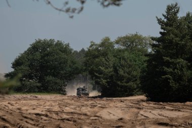 Askeri konvoy, taktik tatbikat sırasında tozlu arazide hareket ediyor.