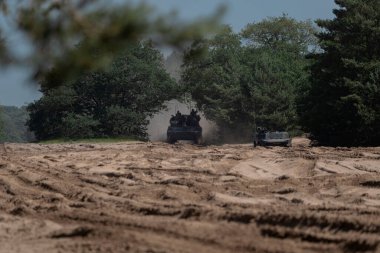 Eğitim tatbikatı sırasında toz ve arazi sorunları olan askeri araçlar taktik düzende konuşlanıyor.