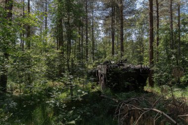Ormanlık alanda yoğun kamufle edilmiş askeri destek aracı.