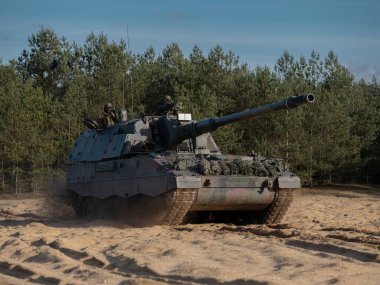 Topçu ekibi saha eğitim ortamında kendi kendine hareket eden bir havan topu kullanıyor.