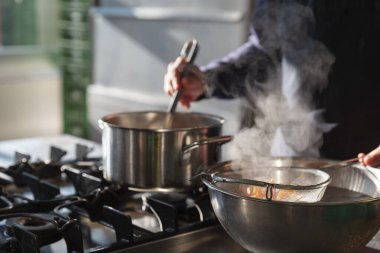 Mutfakta buharda pişen sebzelerle birden fazla tencereyi idare eden profesyonel bir şef.