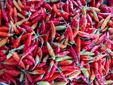 Çerçeveyi dolduran canlı kırmızı ve yeşil biber yığınının genel görünümü, mutfak ya da tarımsal pazarlama için uygun baharatlı ve renkli bir gıda arka planı yaratıyor..