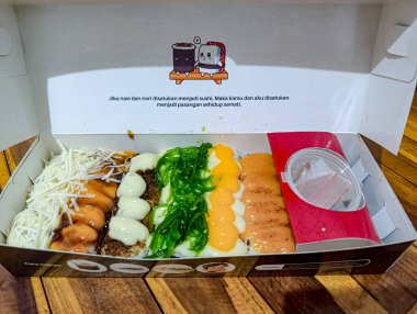 Çeşitli suşi çeşitleri ahşap bir masada çeşitli aromalar ve mutfak sunumları sergilenen çeşitli malzemelerle beyaz bir kutuda sergileniyor, yiyeceklerle ilgili promosyonlar için mükemmel..