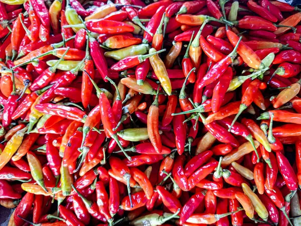 Bir yığın küçük kırmızı biber, bazıları yeşil saplı, canlı, renkli bir sahne yaratıyor. Mutfak malzemeleri ya da yiyeceklerle ilgili promosyonlar için ideal..