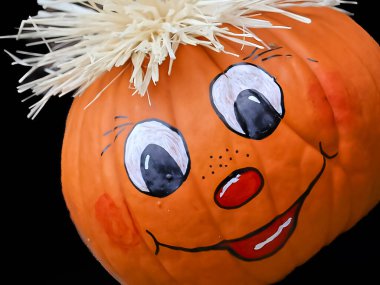 Canlı bir turuncu balkabağı el boyaması gülümseyen bir yüzle, büyük beyaz gözbebekleri, kırmızı yanakları ve küçük kırmızı bir burnu ve ağzı ile süslenir. Yüksek kalite fotoğraf