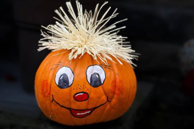 Canlı bir turuncu balkabağı el boyaması gülümseyen bir yüzle süslenir, büyük beyaz gözbebekleri, kırmızı yanakları ve küçük kırmızı bir burnu ve ağzı vardır..