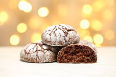 Bir yığın ev yapımı, lezzetli ve yarım yamalak kurabiyelerle bulanık, sıcak Noel ışıklarına karşı. Seçici odak ve alanın sığ derinliği