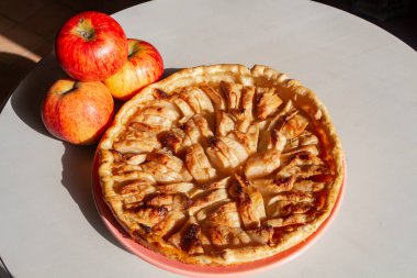 Bir tabak ve üç elma üzerinde ev yapımı elma tart