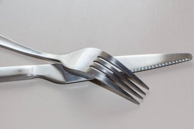 Çatal ve bıçak, gri arka planda paslanmaz çelikten.