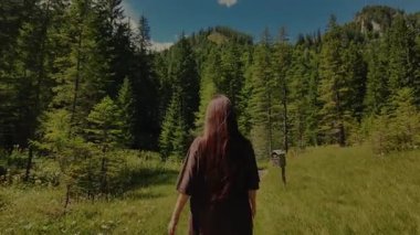 Açık alp sulak arazide tahta bir geçitte yürüyüş yapan kızın yakın çekimi. Avusturya 'nın Hohentauern kentindeki yemyeşil çam ağaçları, otlar ve çevresindeki tepeler. Deniz kenarındaki manzaralı yürüyüş yolu.