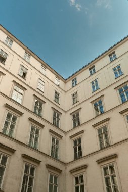 Viyana 'nın beyaz klasik bina köşesinin yukarı doğru perspektifi, açık mavi gökyüzüne karşı mimari detayları vurguluyor.