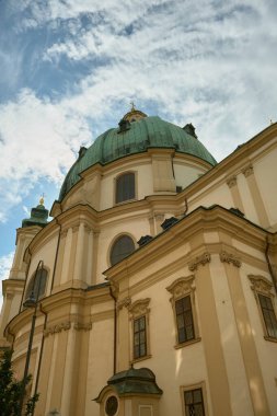 Viyana 'daki bir katedralin dramatik alçak açılı görüntüsü mimari detayları vurguluyor ve açık mavi gökyüzüne karşı yükselen yeşil kubbe.