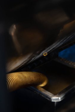 Yellow wasp in flight captured between industrial tubes or coils of agricultural machinery. Motion shot during harvest season showing insect among wine processing equipment.