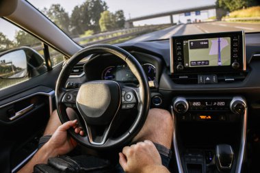 Otobanda direksiyon tutan bir adam var. Konsolda GPS navigasyonu var..