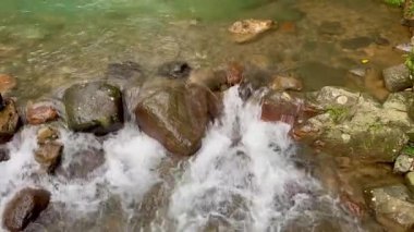 Yumuşak bir nehir taşları üzerinde huzurlu bir şekilde akar doğal ortamda, sakinleştirici ve sakin bir sahne yaratarak doğal arka plan ya da rahatlama teması için mükemmeldir.