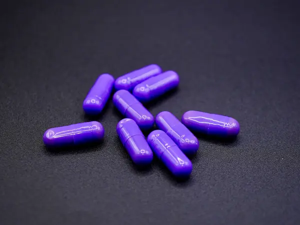 Sağlık konuları, reçeteli ilaçlar veya tıbbi makaleler ve ürün kataloglarındaki diyet takviyelerini resmetmek için siyah arka planda izole edilmiş mor haplar