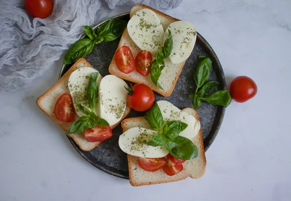Bread with mozzarella cheese, tomato on a light background