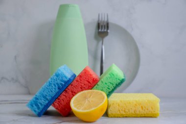 Bir şişe bulaşık deterjanı, limon, arka planda sünger.