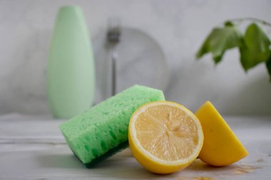 Bir şişe bulaşık deterjanı, limon, arka planda sünger.