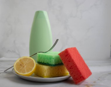 Bir şişe bulaşık deterjanı, limon, arka planda sünger.