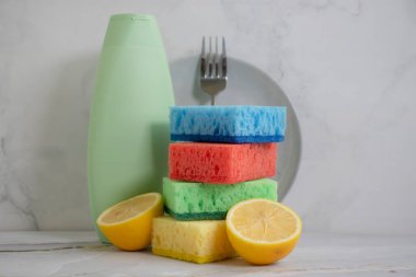 Bir şişe bulaşık deterjanı, limon, arka planda sünger.