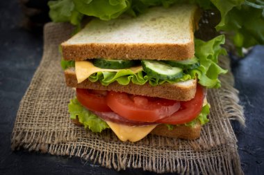 Peynirli sandviç, sosis, domates, marul, eski arkaplanda mavi soğan.