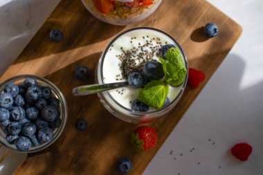 Yoğurt, chia tohumu, yabanmersini, çilek, ahududu, hafif arkaplanda nane.