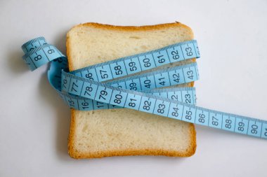 Piece of white bread measuring tape on a light background