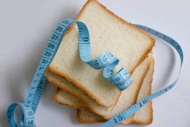 Piece of white bread measuring tape on a light background