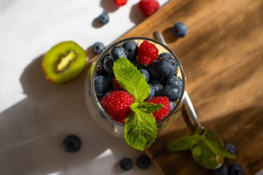 Yogurt, chia seeds, blueberries, strawberries, raspberries, mint, kiwi on a light background